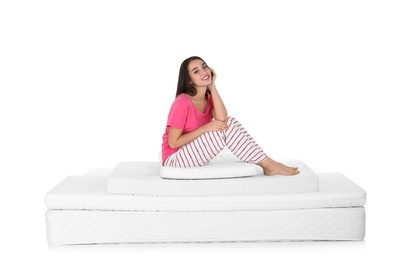 Photo of Young woman sitting on mattress pile against white background