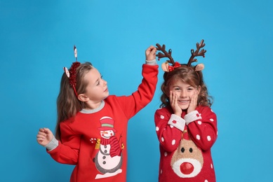 Kids in Christmas sweaters and festive accessories on blue background