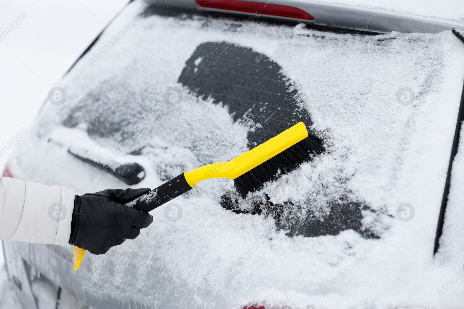 Photo of Man cleaning snow from car window outdoors, closeup