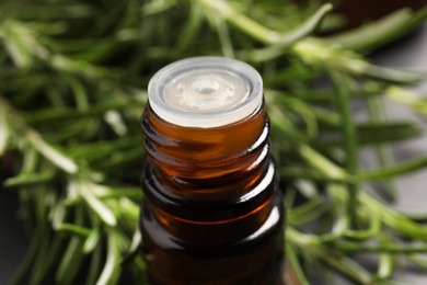 Photo of Bottle of rosemary oil on blurred background, closeup
