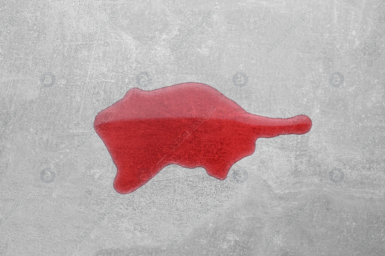 Photo of Puddle of red liquid on light grey surface, top view