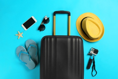 Photo of Flat lay composition with suitcase and traveler's accessories on color background