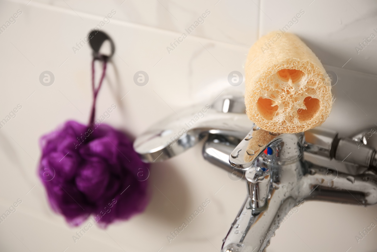 Photo of Purple shower puff and loofah sponge in bathroom, closeup