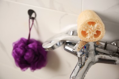 Photo of Purple shower puff and loofah sponge in bathroom, closeup