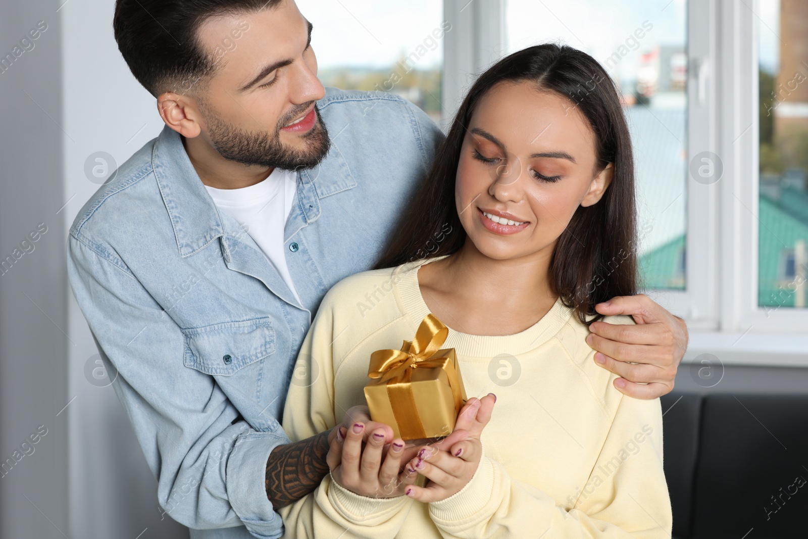 Photo of Man presenting gift to his girlfriend at home