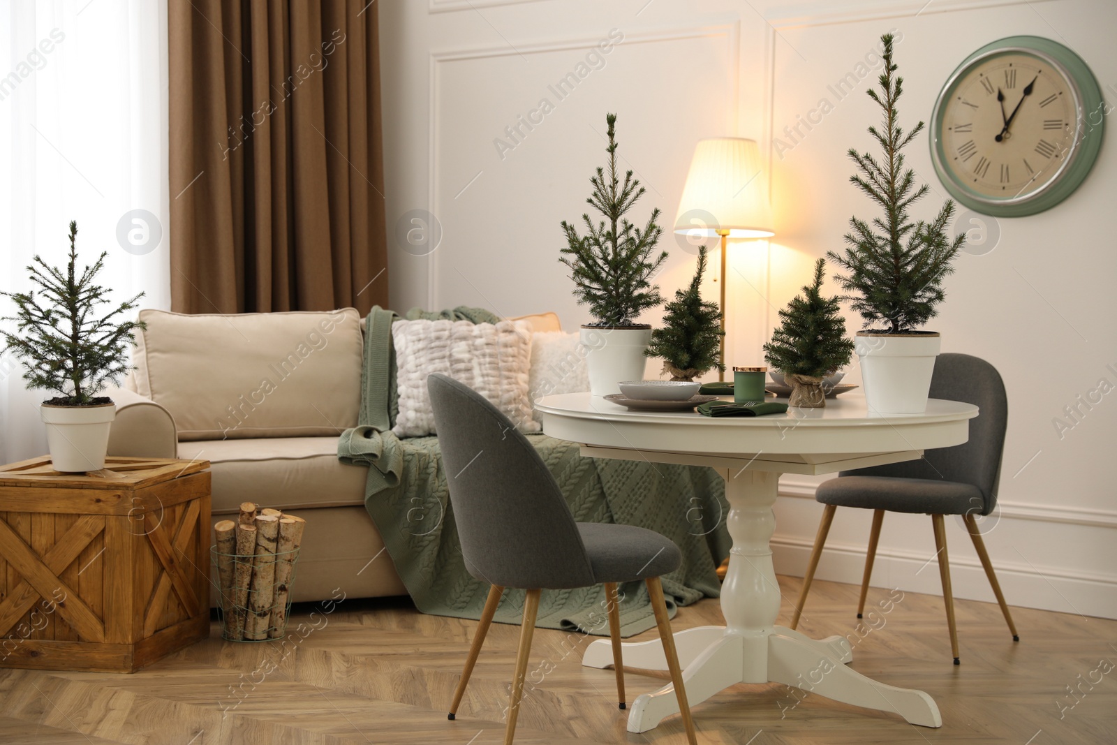 Photo of Beautiful room interior with dining table and potted fir trees. Christmas decor