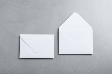 Photo of Simple white paper envelopes on light grey table, flat lay