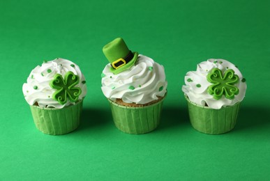 St. Patrick's day party. Tasty festively decorated cupcakes on green table