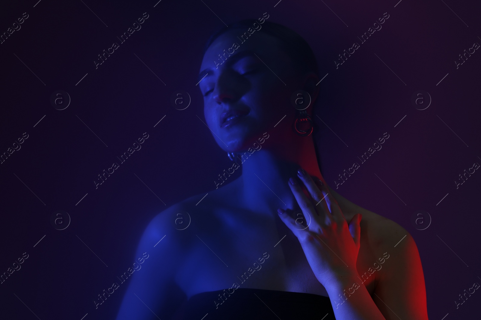 Photo of Portrait of beautiful young woman on color background in neon lights