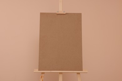 Wooden easel with blank board on beige background