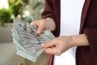 Photo of Money exchange. Woman counting dollar banknotes on blurred background, closeup