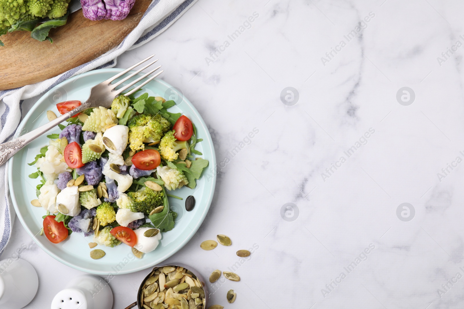 Photo of Delicious salad with cauliflower, tomato and cheese served on white marble table, flat lay. Space for text