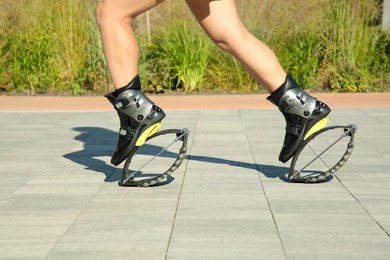 Photo of Woman doing exercises in kangoo jumping boots outdoors, closeup