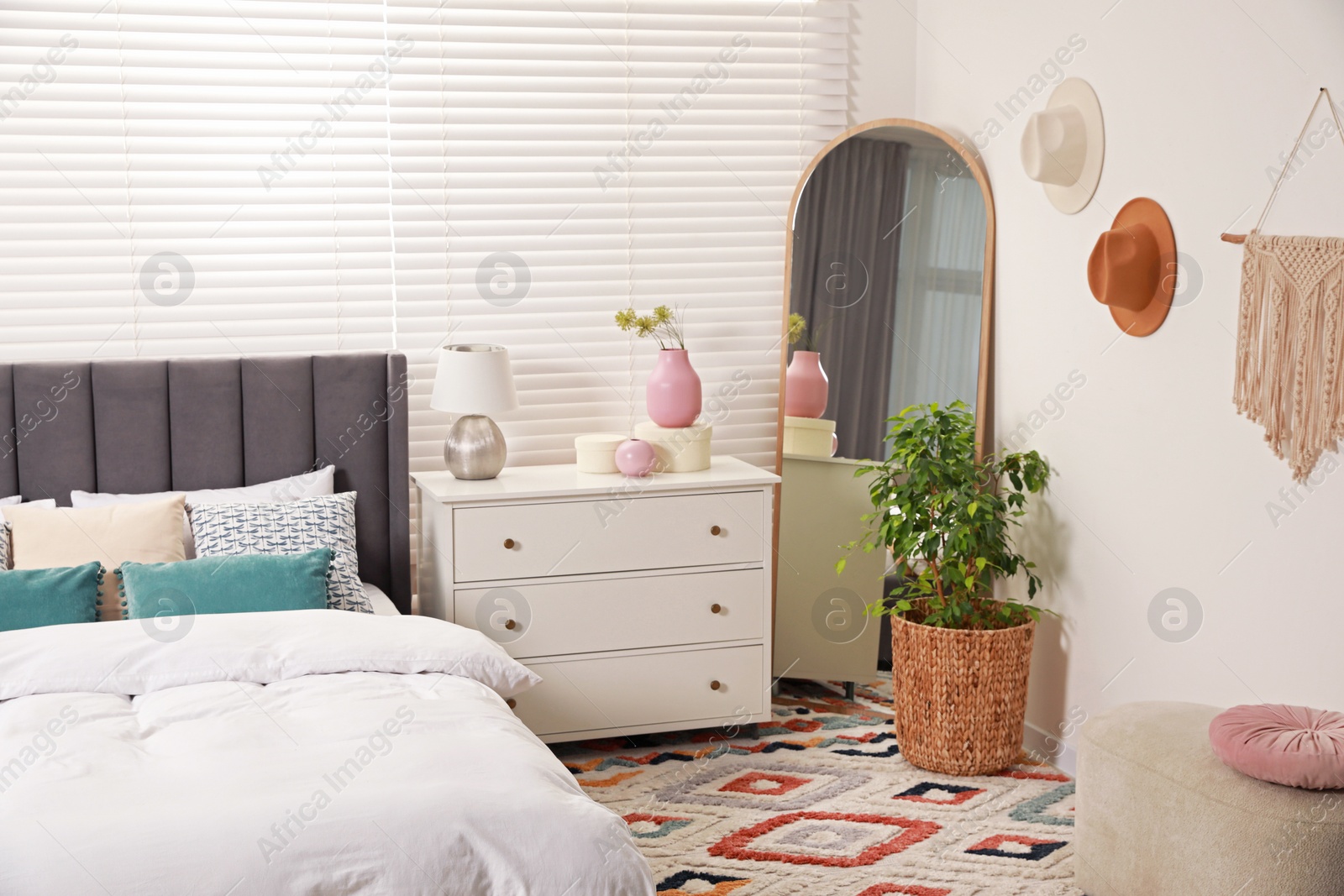 Photo of Comfortable bed with cushions, houseplant and different decor elements in room. Stylish interior