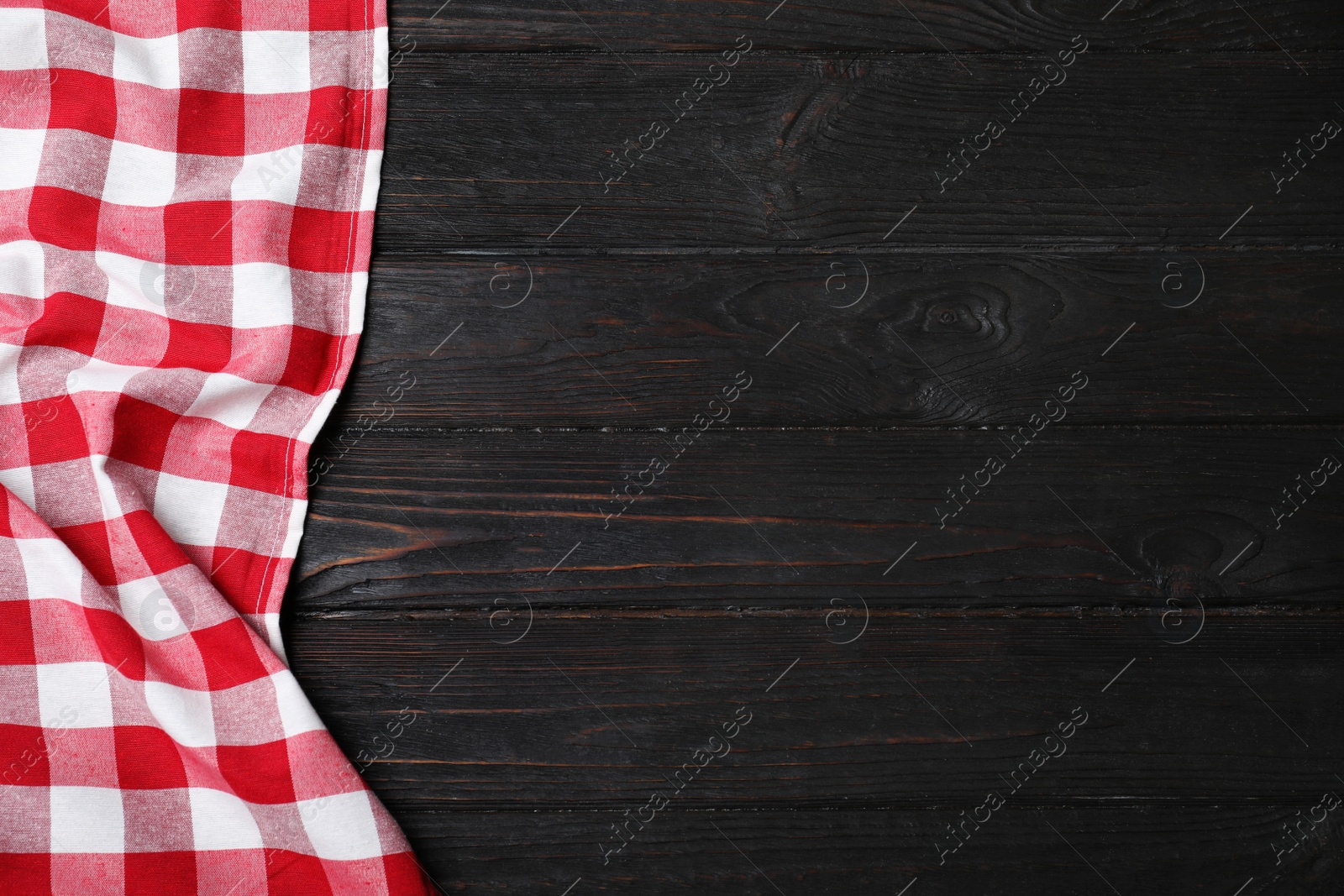 Photo of Checkered picnic blanket on color wooden background, top view. Space for text