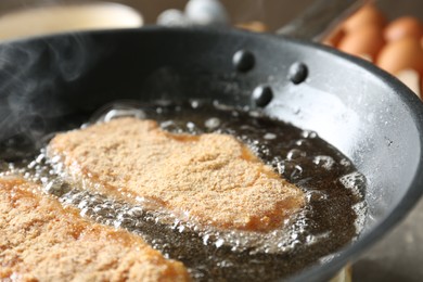 Photo of Cooking schnitzels in frying pan, closeup view