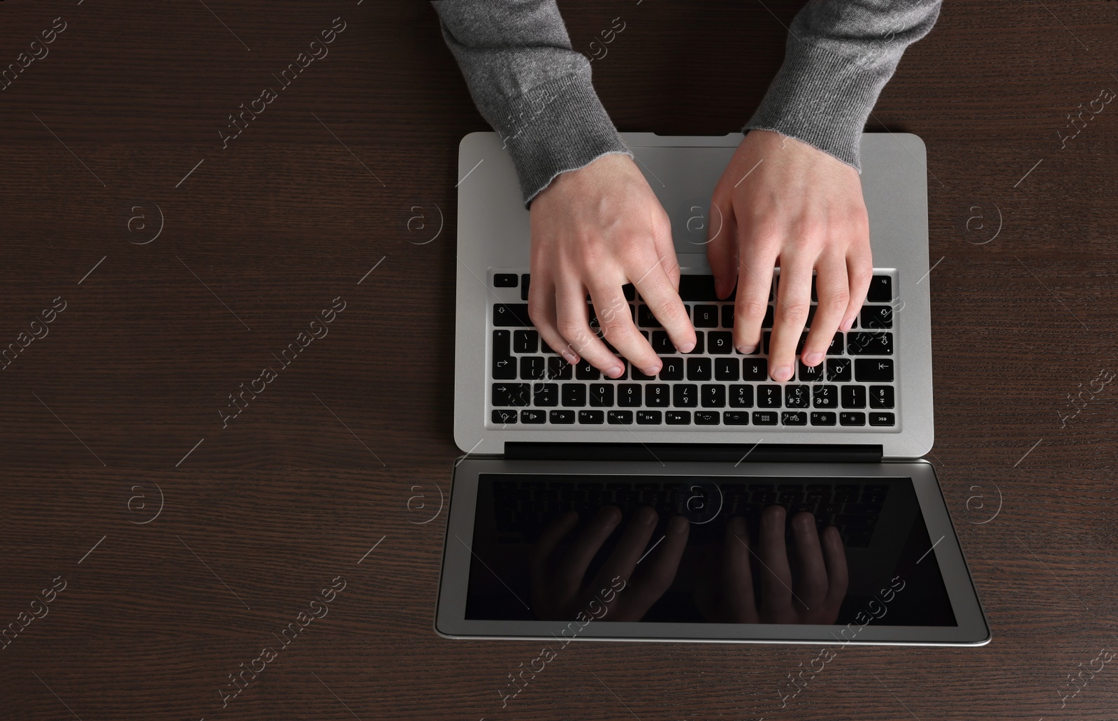 Photo of Man working with laptop at wooden table, top view. Space for text