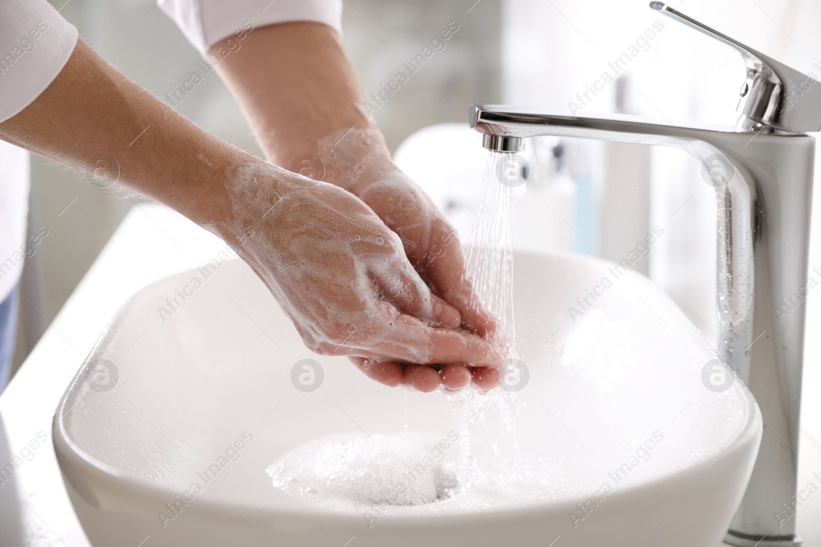 Photo of Man washing hands with soap over sink in bathroom, closeup