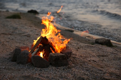 Photo of Beautiful bonfire with burning firewood on beach in evening
