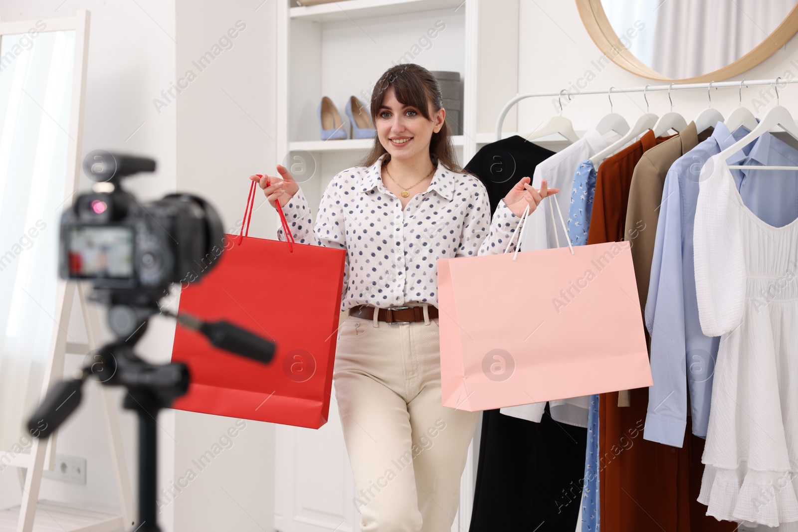 Photo of Smiling fashion blogger with shopping bags recording video at home