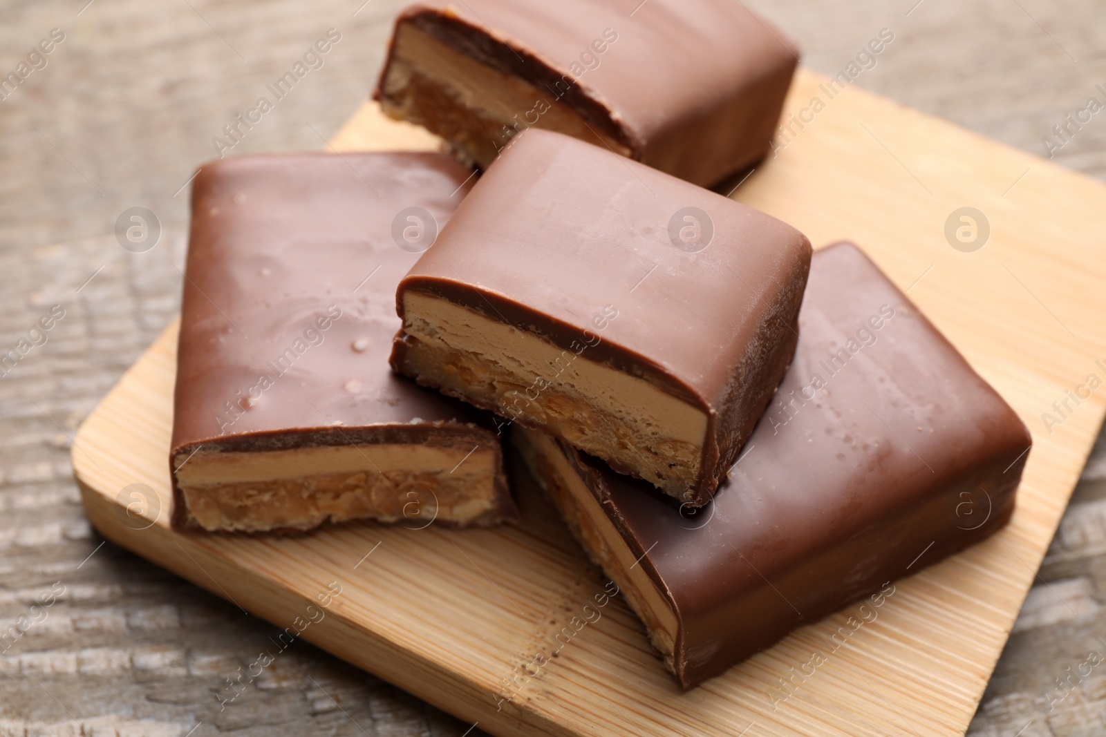 Photo of Tasty chocolate bars with nougat on wooden table, closeup