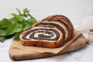 Photo of Cut poppy seed roll on white marble table, closeup. Tasty cake