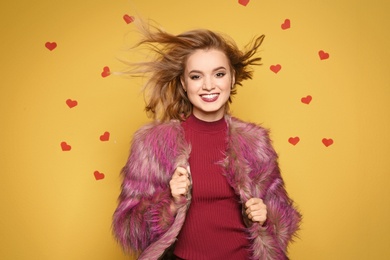 Photo of Beautiful young woman in fur coat posing on color background