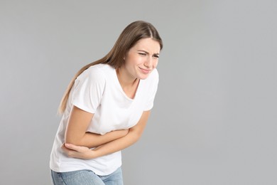 Photo of Woman suffering from stomach ache on grey background, space for text. Food poisoning