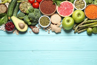 Fresh vegetables, fruits and seeds on light blue wooden table, flat lay. Space for text