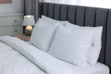 Photo of Soft white pillows and duvet on bed at home