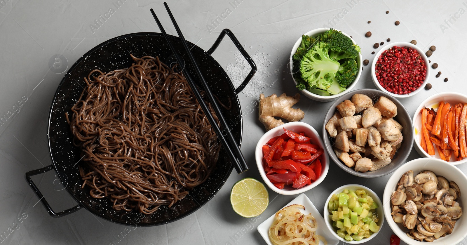 Photo of Wok with noodles, chicken and other products on light grey table, flat lay