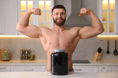 Photo of Young man with jar of protein powder at white marble table in kitchen