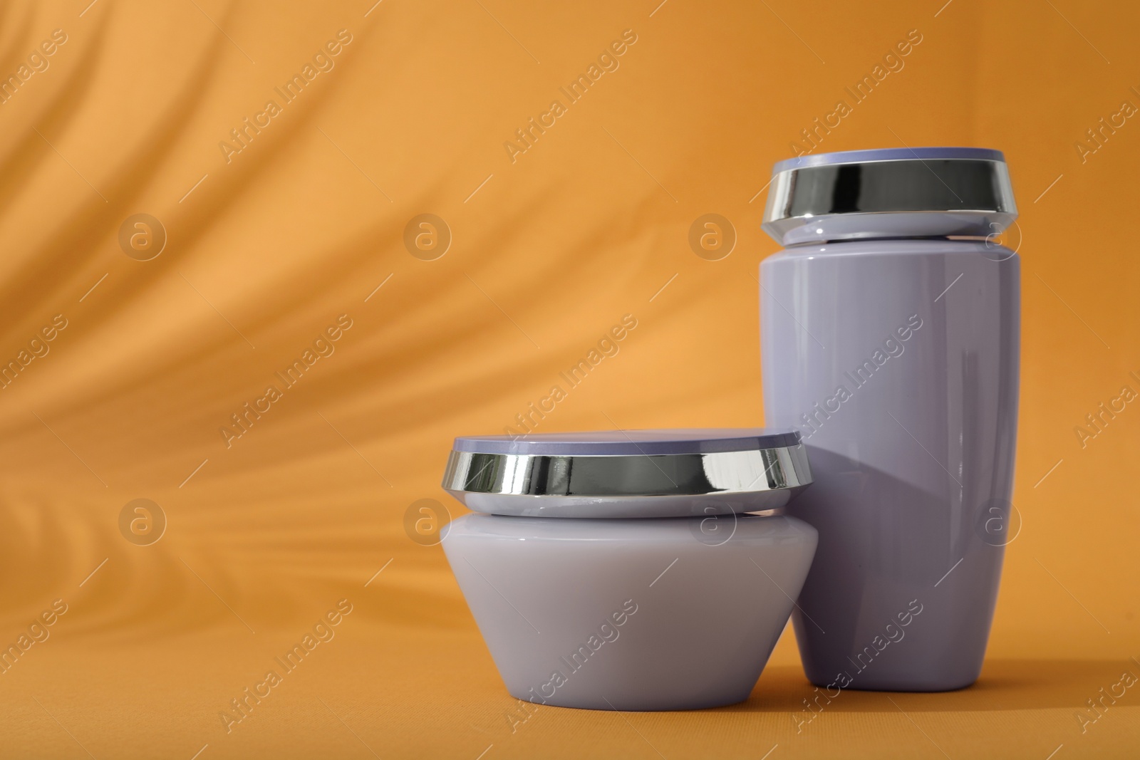 Photo of Hair care cosmetic products on orange background, space for text