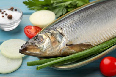 Photo of Delicious salted herring and ingredients on light blue wooden table, closeup