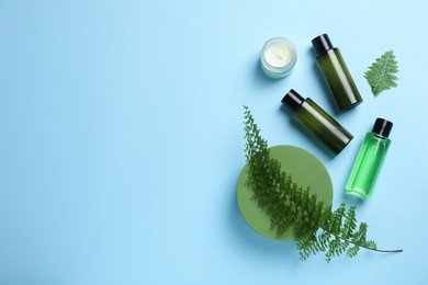 Photo of Different skin care products and fern on light blue background, flat lay. Space for text