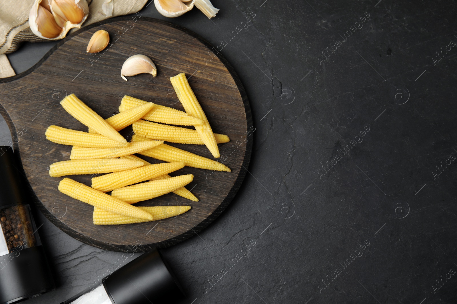 Photo of Fresh baby corn cobs served on black table, flat lay. Space for text