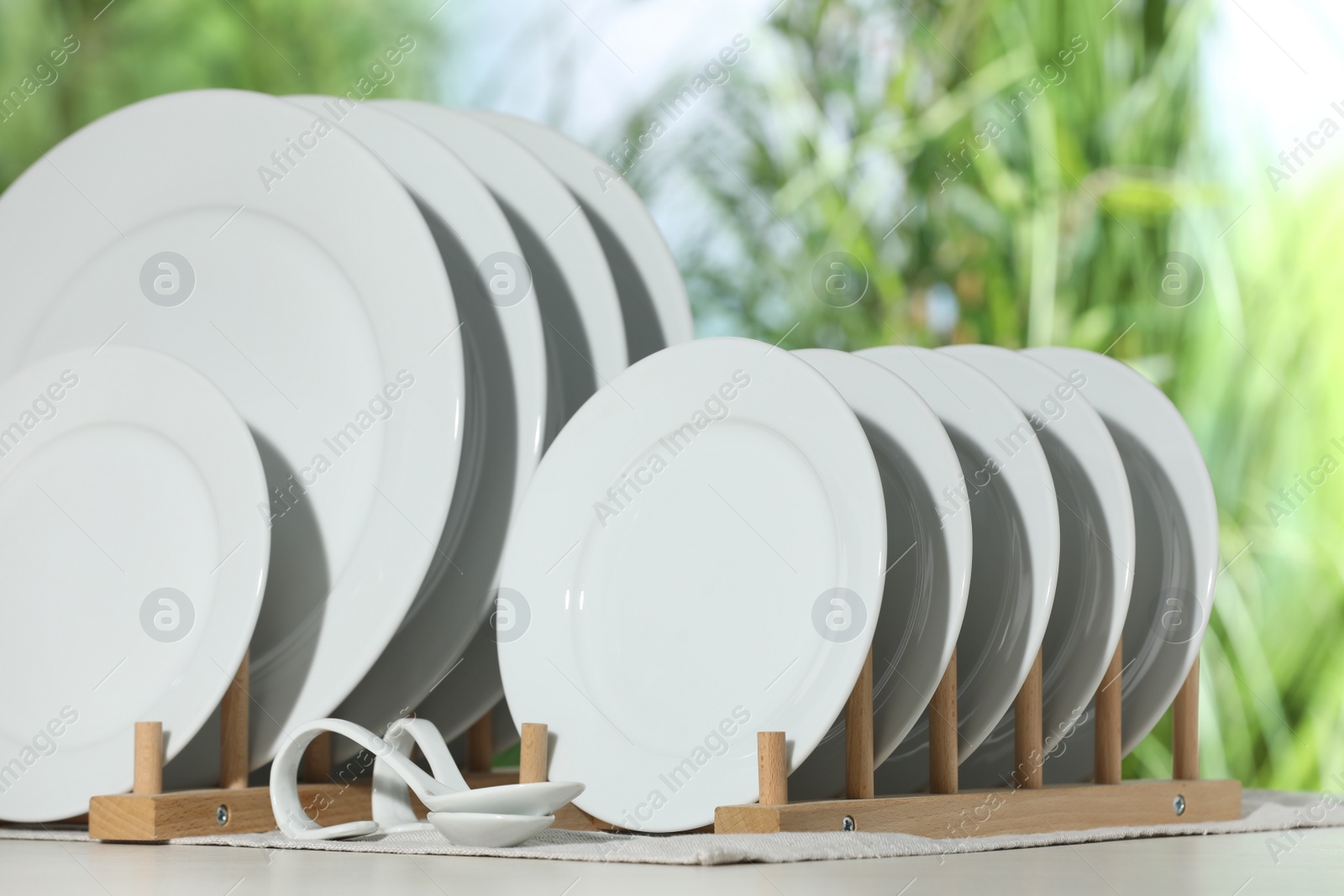 Photo of Set of clean dishware on white table against blurred background