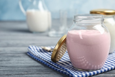 Jar with tasty yogurt on table