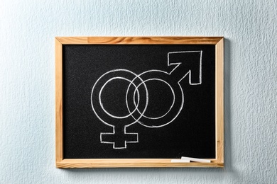 Photo of Small blackboard with drawn gender symbols on white wall. Sex education