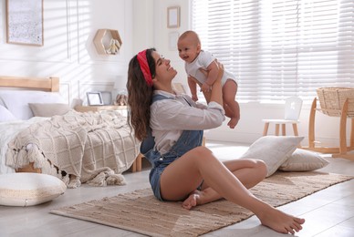 Photo of Happy young mother with her cute baby on floor in bedroom
