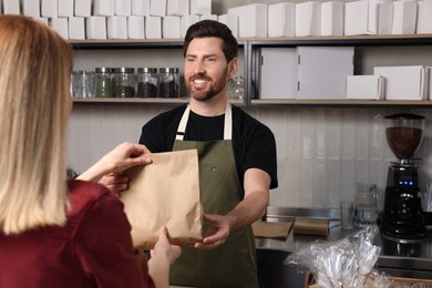 Photo of Seller giving customer fresh pastries in bakery shop