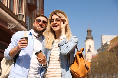 Happy couple with coffee on city street in morning