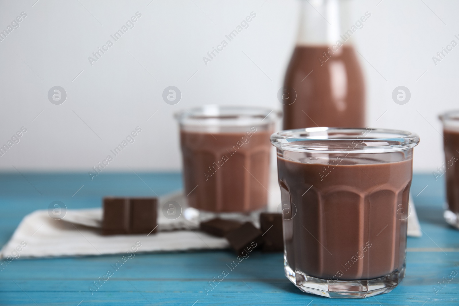 Photo of Delicious chocolate milk on light blue wooden table. Space for text