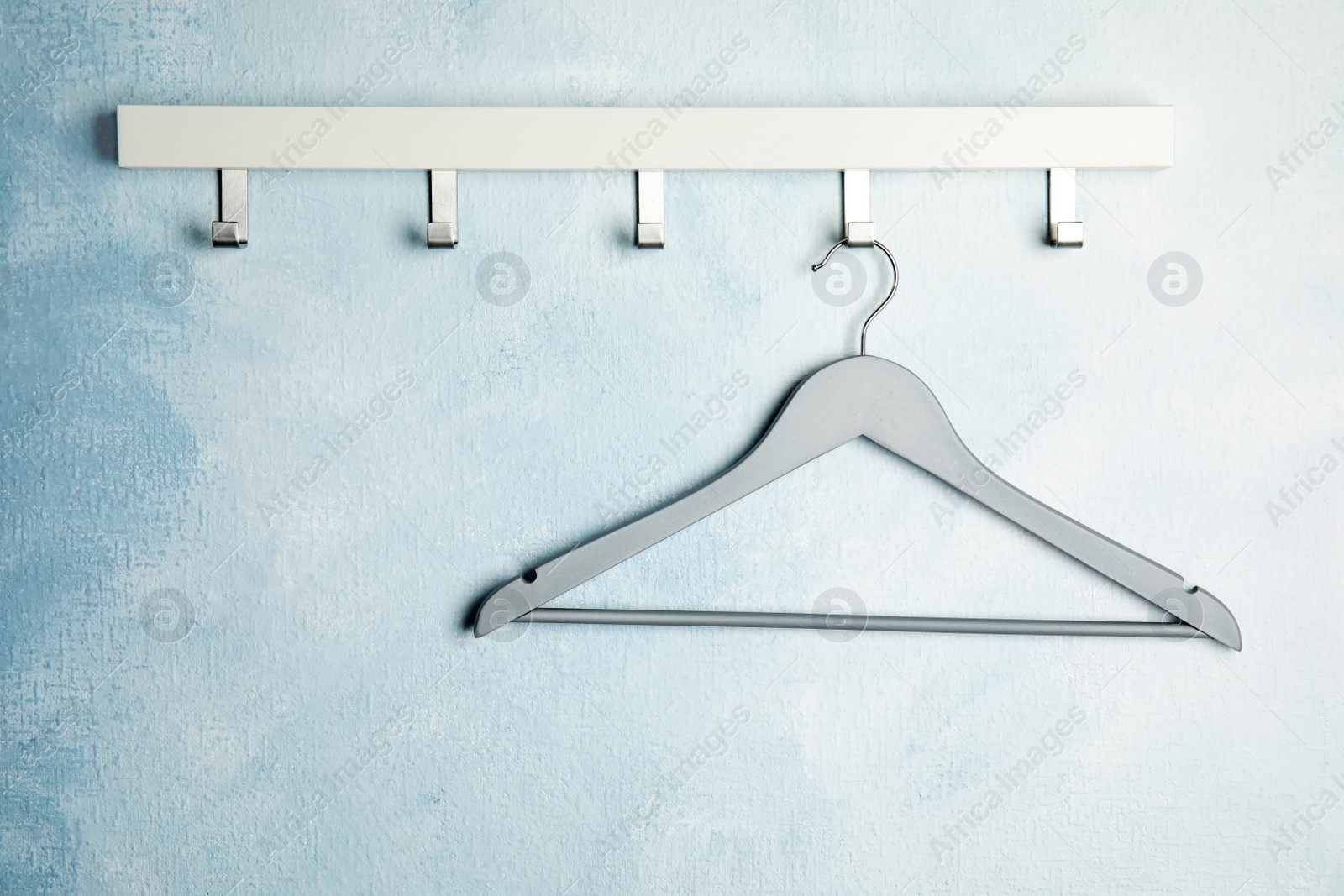 Photo of Rack with empty clothes hanger on color wall, space for text. Wardrobe accessory