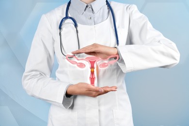 Image of Doctor demonstrating virtual icon with illustration of female reproductive system on light background, closeup. Gynecological care 