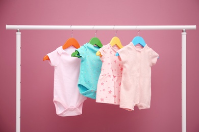 Photo of Baby clothes hanging on rack against color background