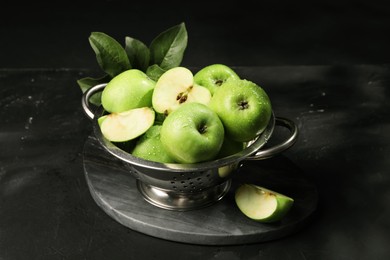 Ripe green apples with water drops and leaves on black table