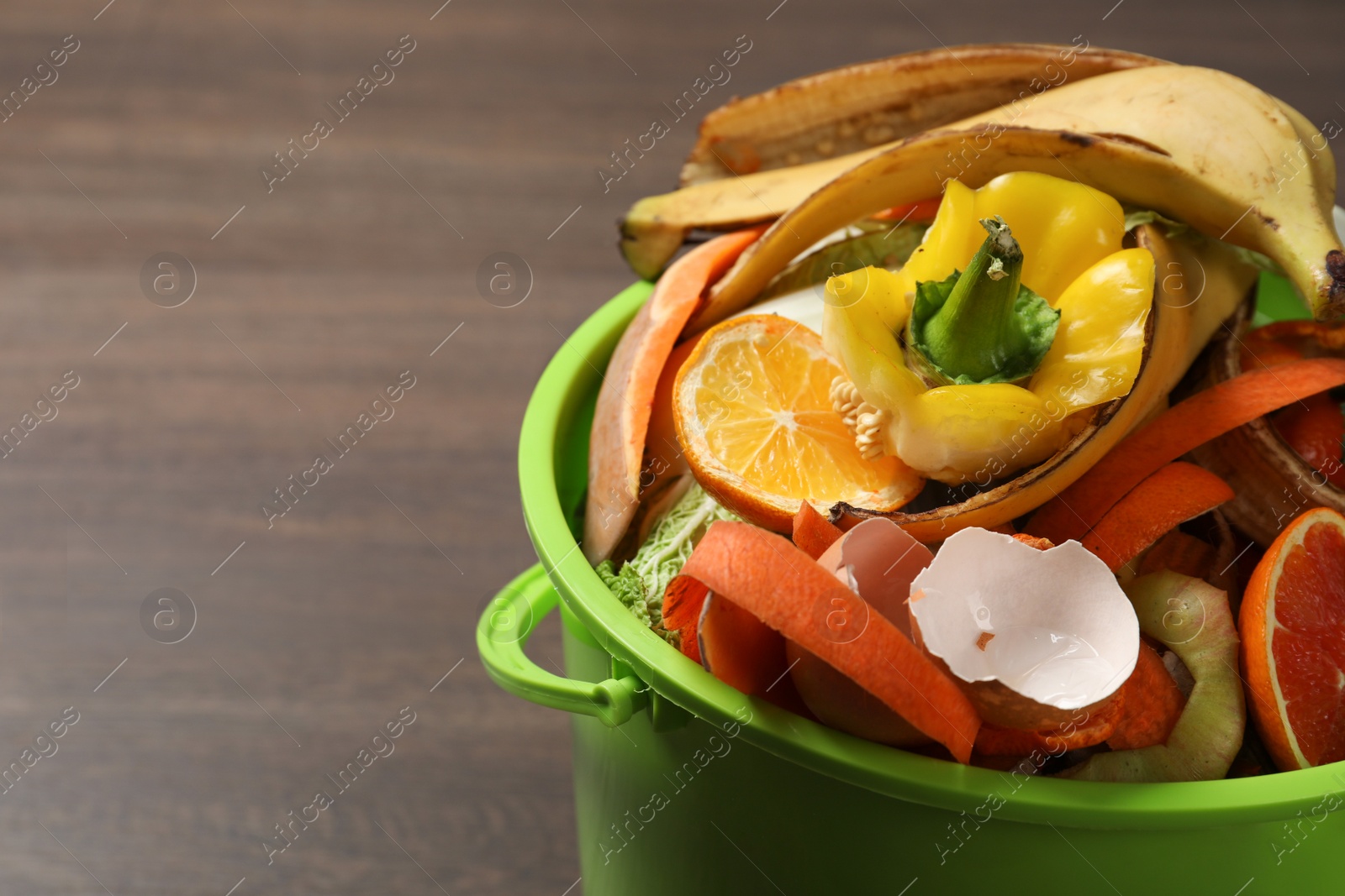 Photo of Natural garbage in trash bin on wooden background, closeup with space for text. Composting of organic waste