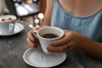 Photo of Woman with cup of fresh aromatic coffee at table, closeup