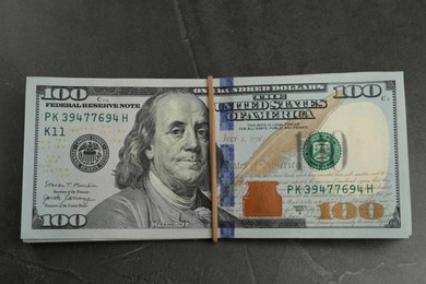 Photo of Money exchange. Dollar banknotes on dark gray textured background, top view